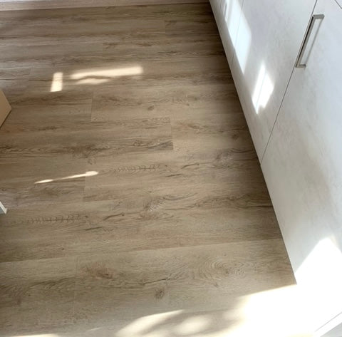 Küchenbereich mit Klebevinylboden Eiche Fiducia in heller Holzoptik und weißen Schränken – pflegeleichter Vinylboden vom Laminat Fachhandel Laminatshop24