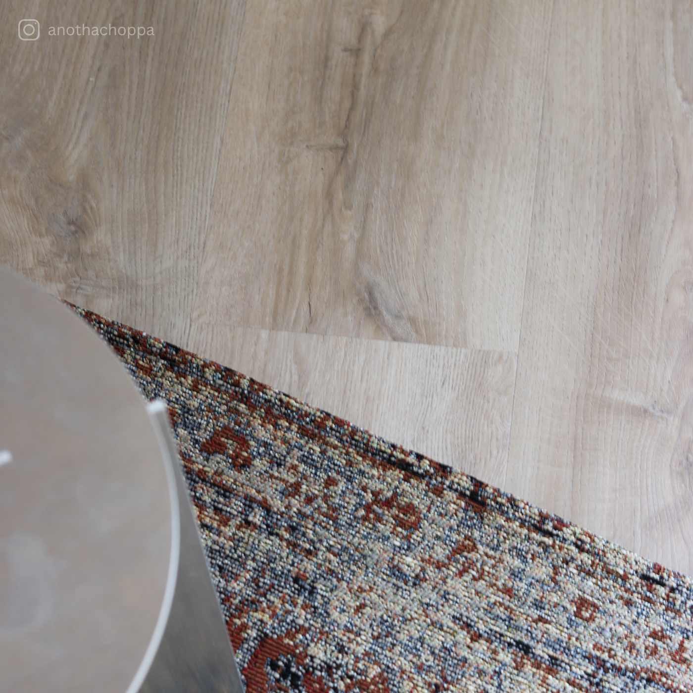 Detailaufnahme des Klebevinyls Eiche Mirandus in heller Holzoptik mit orientalischem Teppich und modernem Beistelltisch – natürlicher Vinylboden von Laminatshop24