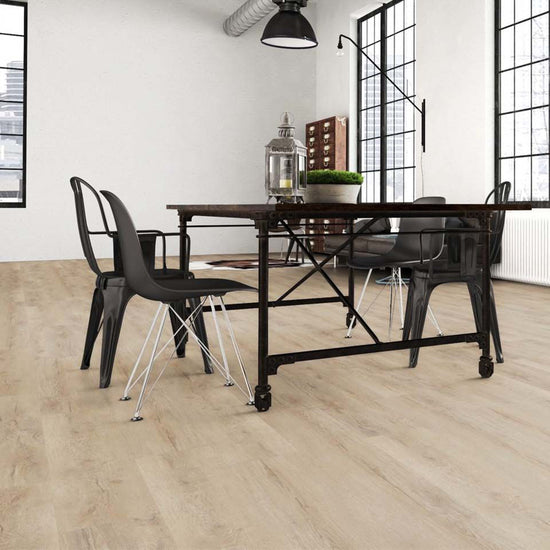 Industrial-Essbereich mit Klick-Vinylboden Eiche Fiducia in heller Holzoptik, schwarzem Metalltisch, Designstühlen und großen Loftfenstern – moderner Vinylboden von Laminatshop24